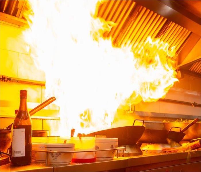 a large flame coming out of cooking pan at restaurant cooking station 