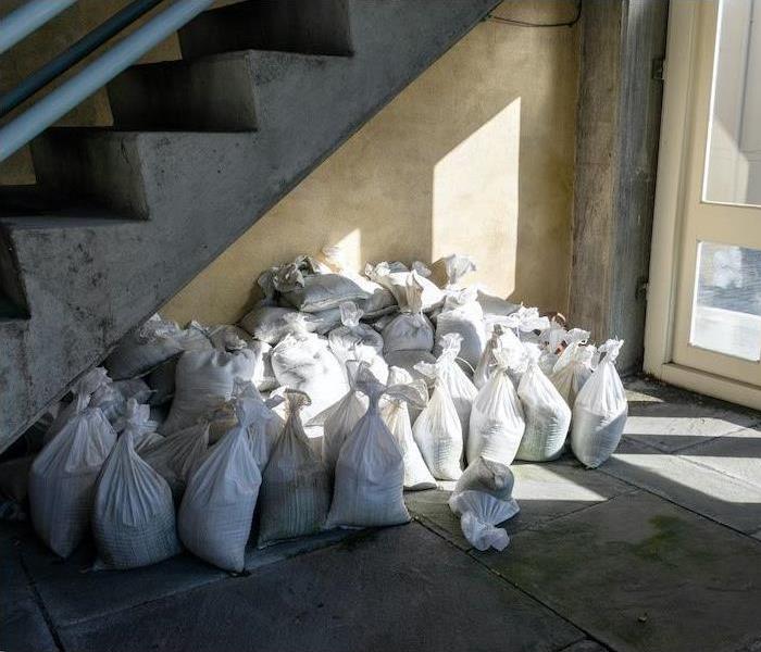 multiple white sandbags at the bottom of a stairway near an exit door